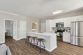 Mount Pleasant apartment for rent - A kitchen with white cabinets and a white island with brown stools.