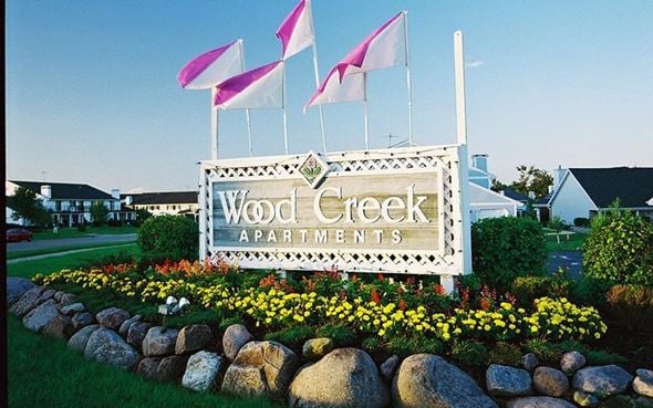 Oak Creek apartment for rent - a sign for wood creek apartments with flags on top of it