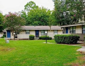 Hinesville apartment for rent - a white house with blue doors and a green yard