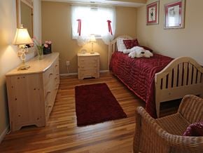 Baltimore apartment for rent - A bedroom with a red rug and a white teddy bear on the bed.
