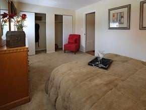 Baltimore apartment for rent - A bedroom with a bed, chair, and a wooden dresser.