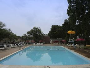 Baltimore apartment for rent - A large blue swimming pool with a diving board and lounge chairs around it.