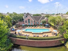 Houston townhouse for rent - A pool surrounded by a brick wall and lounge chairs.