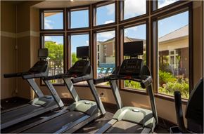 Katy apartment for rent - a gym with cardio machines and a view of a swimming pool