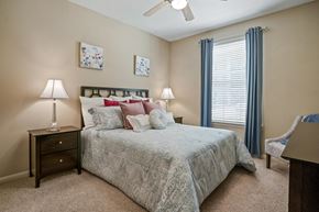 Conroe apartment for rent - A bedroom with a bed, two lamps, and a ceiling fan.