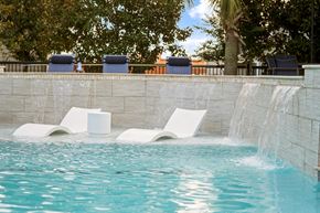 Conroe apartment for rent - A pool with a waterfall and two lounge chairs.