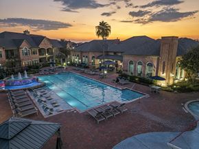 Houston apartment for rent - A large outdoor swimming pool surrounded by lounge chairs and umbrellas.