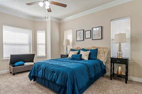 Houston apartment for rent - A bedroom with a blue bedspread and a ceiling fan.