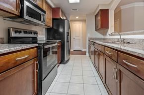 Houston apartment for rent - A kitchen with brown cabinets and black appliances.