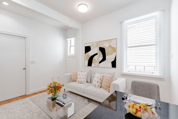 San Francisco apartment for rent - A modern living room with a white couch, a coffee table with a vase of flowers, and a painting on the wall.