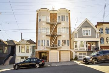 San Francisco apartment for rent - A black car is parked in front of a two-story building with a garage.