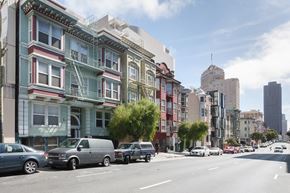 San Francisco apartment for rent - A row of colorful buildings line a street with cars parked on the side.