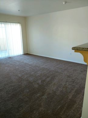 Salinas apartment for rent - Living Room from entrance to kitchen showing carpeted flooring and patio door with blinds.