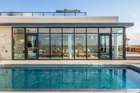 Jersey City apartment for rent - a swimming pool in front of a pool house with glass doors