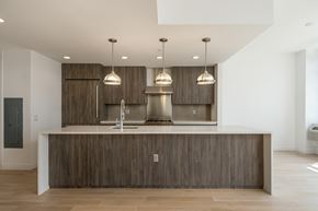 Jersey City apartment for rent - a kitchen with wooden cabinets and a large island with three lights