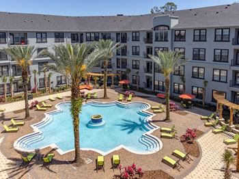 Large swimming pool surrounded by four palm trees, plenty of sunning chairs