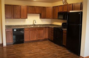 Dickinson apartment for rent - a kitchen with black appliances and wooden cabinets