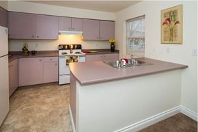 Anchorage townhouse for rent - A kitchen with pink cabinets and a white refrigerator.