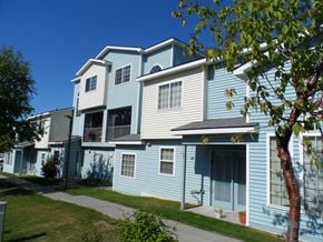 Anchorage townhouse for rent - A blue and white two story apartment building with a tree in front.