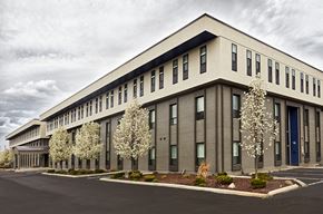 Madison Heights apartment for rent - A modern building with a grey facade and white flowering trees in front.