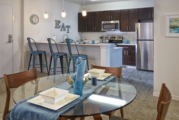 Madison Heights apartment for rent - A dining table set with plates and napkins is in the foreground of a kitchen.