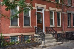 Jersey City apartment for rent - A red brick building with a black iron fence in front.