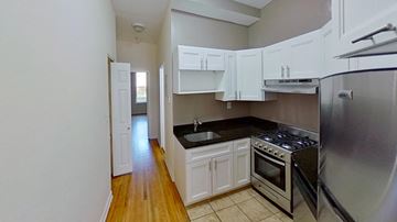 Jersey City apartment for rent - A kitchen with white cabinets and a stainless steel refrigerator.