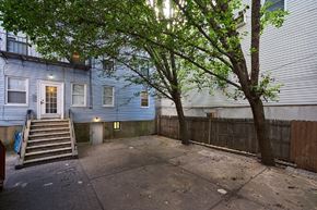 Jersey City apartment for rent - A tree in front of a blue house with a white door.