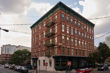 Jersey City apartment for rent - A red brick building with a green roof and a fire escape on the side.