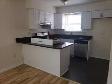 Jersey City apartment for rent - A kitchen with white cabinets and a black countertop.