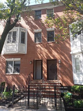 Jersey City apartment for rent - A red brick house with a white window and a brown door.