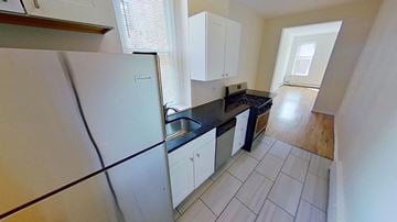 Jersey City apartment for rent - A kitchen with white cabinets and a black countertop.