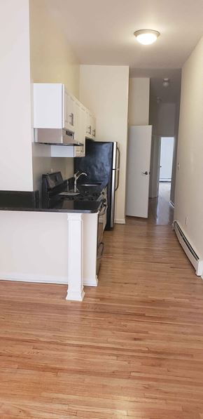 Jersey City apartment for rent - A kitchen with a black fridge and white cabinets.