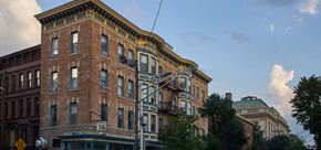 Jersey City apartment for rent - A tall brick building with a yellow trim and a green roof.