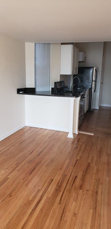 Jersey City apartment for rent - A kitchen with a black counter top and wooden floors.