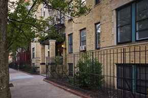 Jersey City apartment for rent - A row of brown brick buildings with green plants growing on the side.
