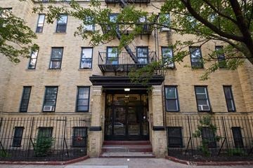 Jersey City apartment for rent - A building with a black iron fence and a tree in front.