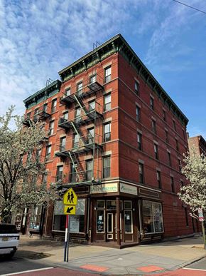 Jersey City apartment for rent - A red brick building with a yellow pedestrian crossing sign in front of it.