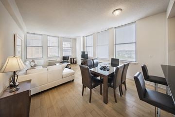 Jersey City apartment for rent - A living room with a white couch and a dining table with chairs.