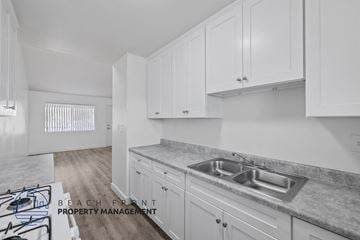 Long Beach apartment for rent - A kitchen with white cabinets and a marble countertop.