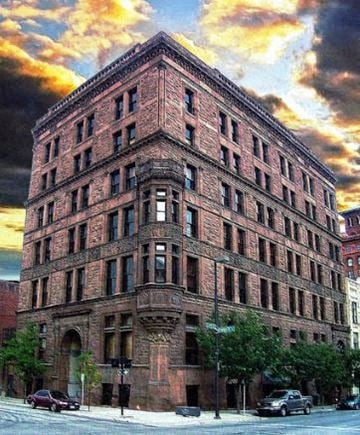 Kansas City apartment for rent - A large red brick building with many windows and a street in front.