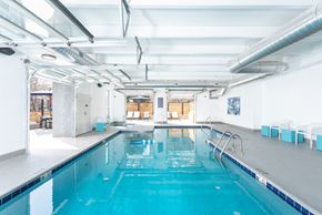 Denver apartment for rent - the indoor swimming pool is located in the center of a large room with white walls