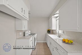 Downey apartment for rent - A kitchen with white cabinets and a countertop with a bowl of fruit on it.