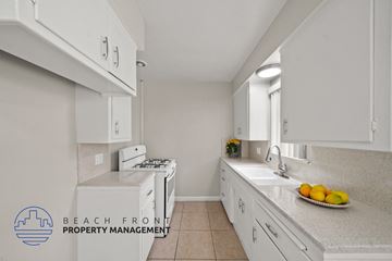 Downey apartment for rent - A kitchen with white cabinets and a countertop with a bowl of fruit on it.