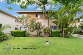 Downey apartment for rent - A well-maintained lawn in front of a building with the logo of Beach Front Property Management.