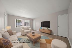 Downey apartment for rent - A living room with a white couch, a brown coffee table, and a flat screen TV on the wall.