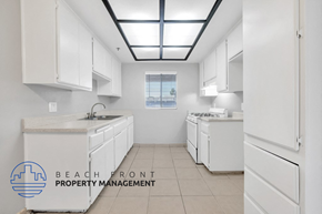 Santa Ana apartment for rent - A clean, white kitchen with a logo for Beach Front Property Management.