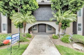Inglewood apartment for rent - a house with a black garage door and palm trees in front of it