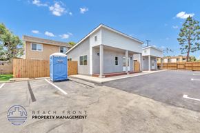 Costa Mesa apartment for rent - A parking lot with a building and a tree in the background.
