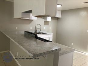Costa Mesa apartment for rent - A kitchen with a marble countertop and white cabinets.